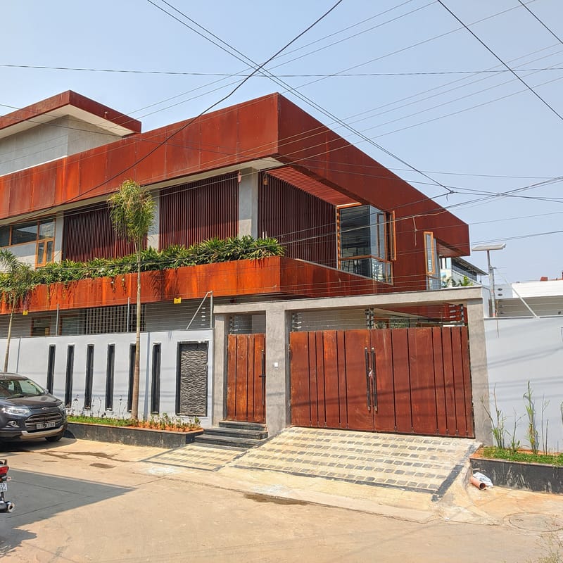 Completed villa with rusted Corten-steel facade, fluted timber gate and planted balcony band, Hyderabad street view