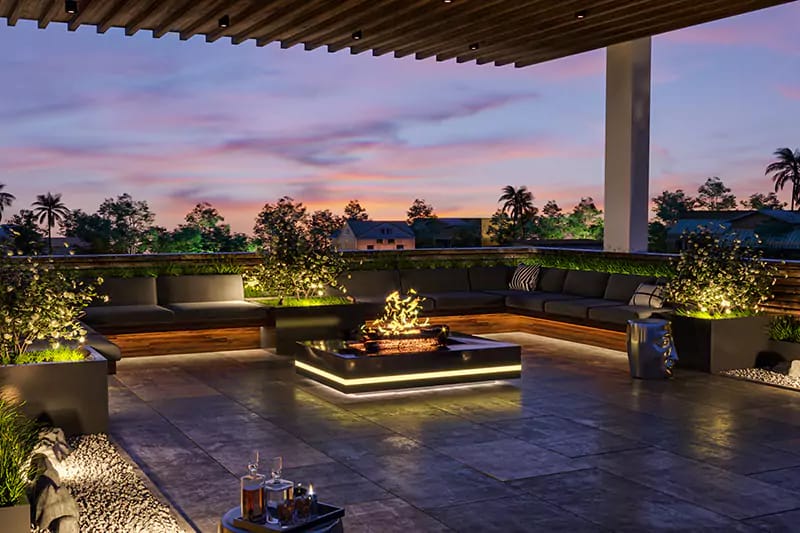 Rooftop terrace lounge at dusk with central fire feature, built-in sofas and lit planters under pergola, Hyderabad