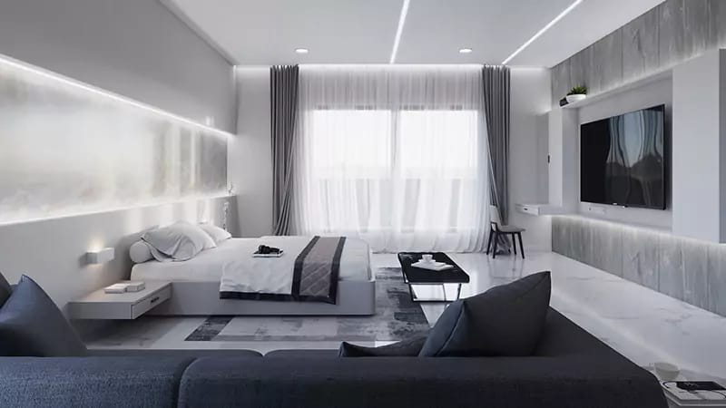 Grey-and-white bedroom with platform bed, backlit niches, wall-mounted TV and navy lounge sofa, Hyderabad
