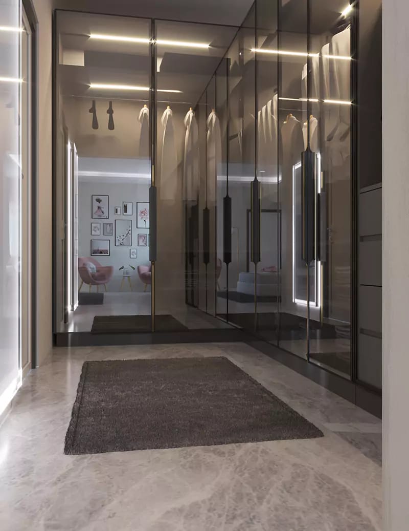 Mirrored glass wardrobe corridor in Hyderabad with warm LED strip lighting, marble floor and grey rug reflecting the bedroom