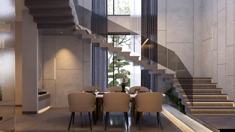 Dining set under a cantilevered stone staircase, beige chairs and gold-base table by a double-height bonsai window, Hyderabad
