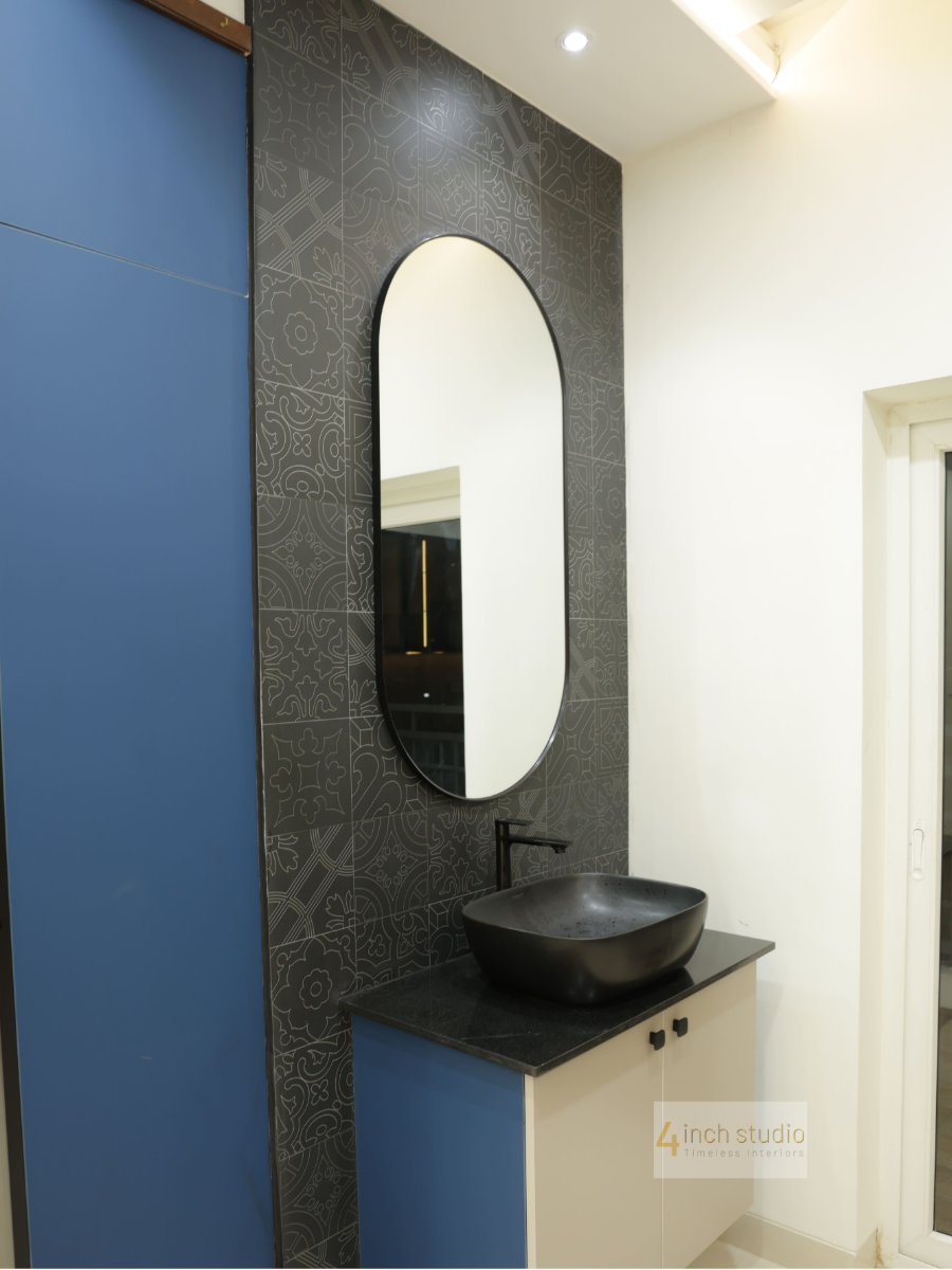 Vanity with black vessel basin, oval mirror, dark patterned-tile feature wall and navy panel, Hyderabad apartment