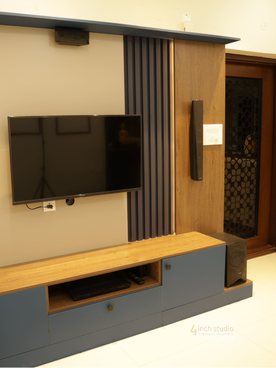 Living-room TV unit on beige wall with navy fluted slats, wood panel and low wood-top media console, Hyderabad
