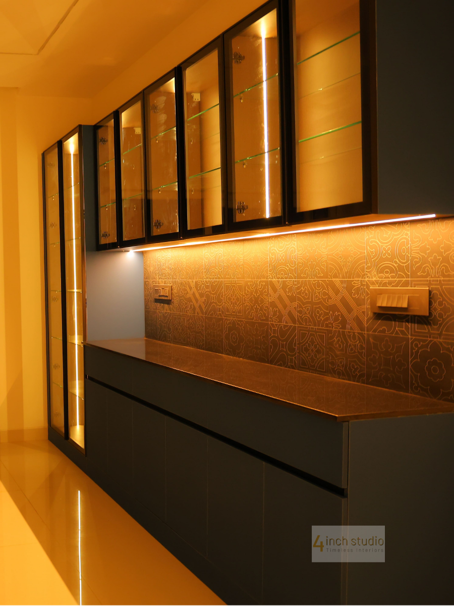 Backlit glass-front crockery unit in charcoal with warm LED glow and patterned tile backsplash, Hyderabad home