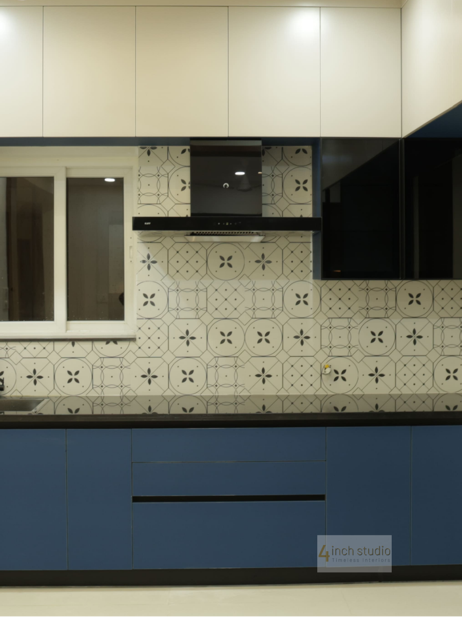 Navy and cream modular kitchen with patterned grey backsplash tiles, black granite counter and chimney, Hyderabad