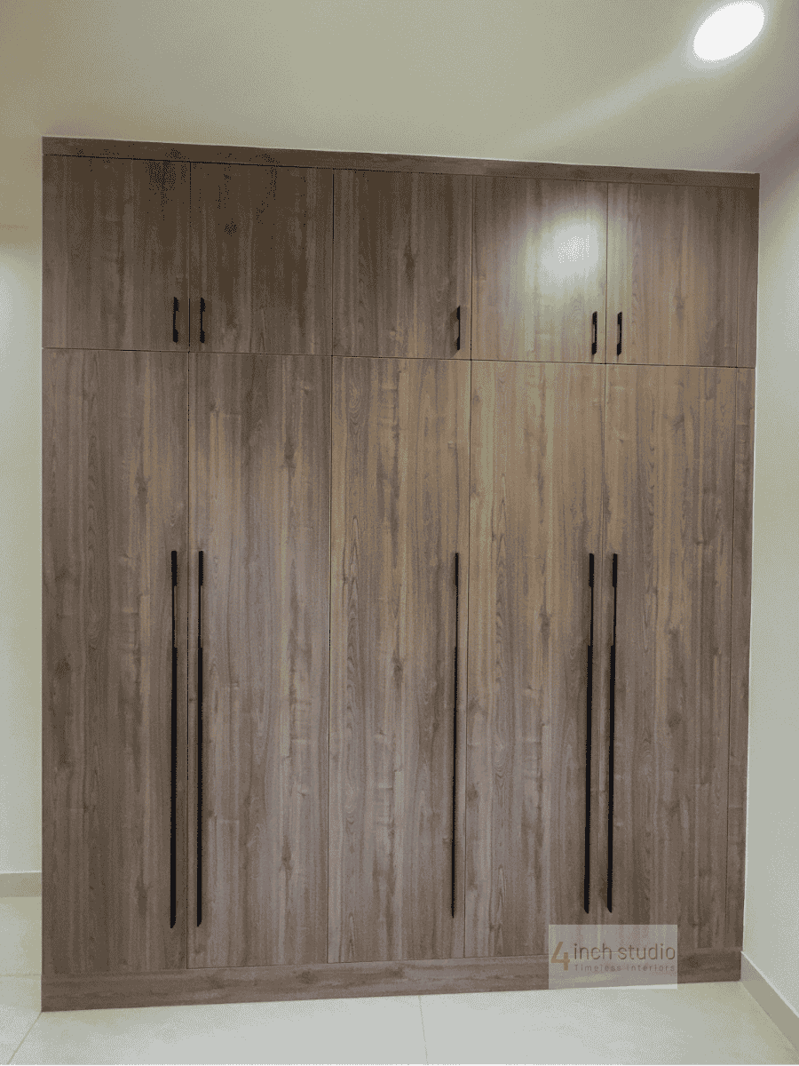 Full-height six-door wardrobe in grey-toned wood with slim black handles against a cream wall, Hyderabad