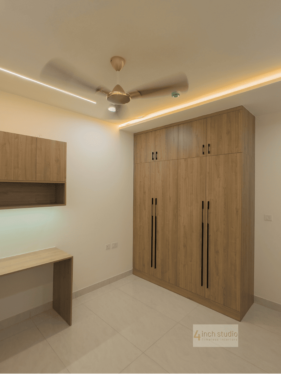 Bedroom study corner in Hyderabad with tall wood-laminate wardrobe, floating desk and cove-lit false ceiling on beige tiles