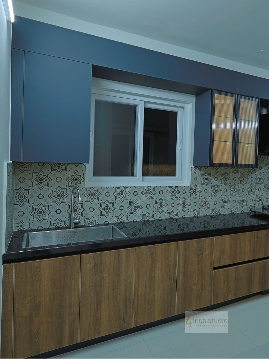Kitchen run with navy upper units, sink under window and Moroccan-pattern tile backsplash over walnut bases, Hyderabad
