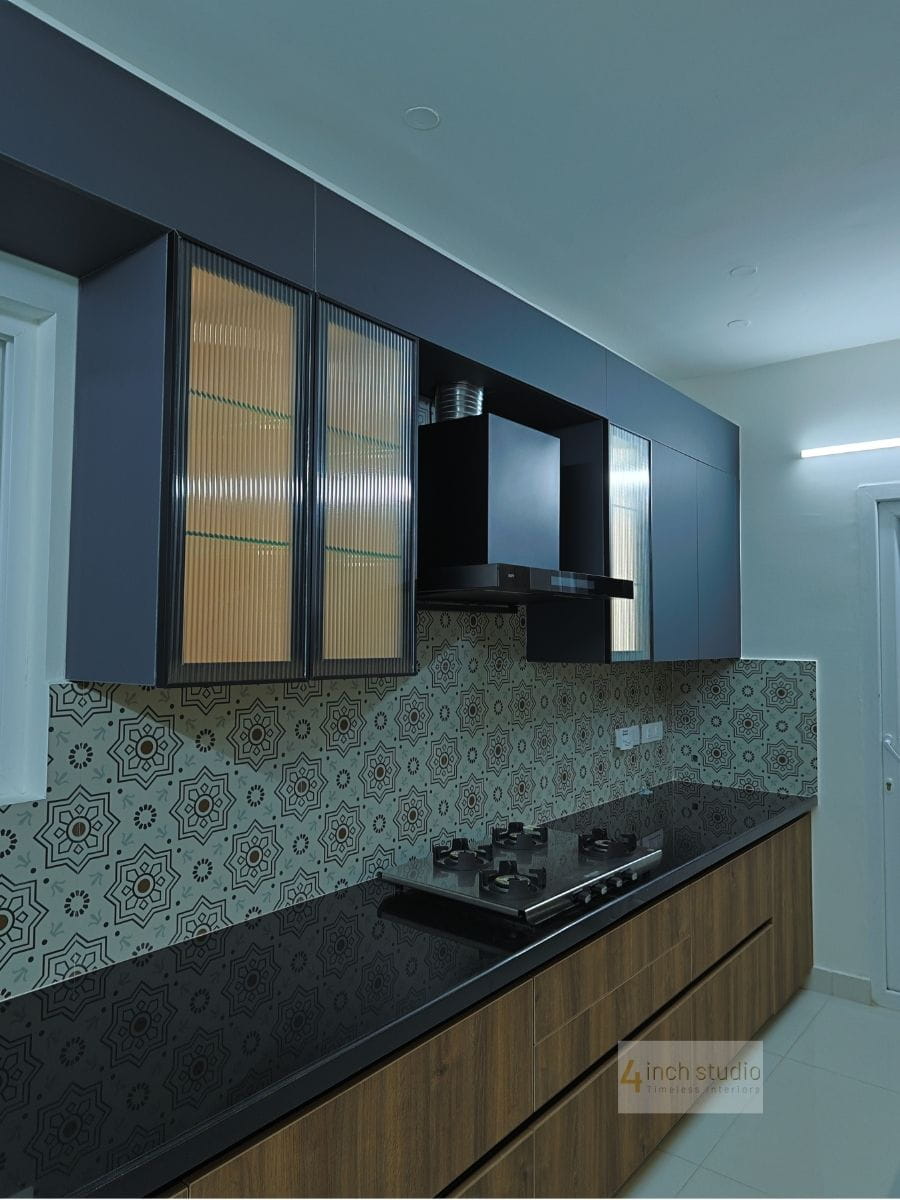 Kitchen with navy cabinets, fluted-glass shutters, black chimney and bold black-and-white Moroccan tile dado, Hyderabad