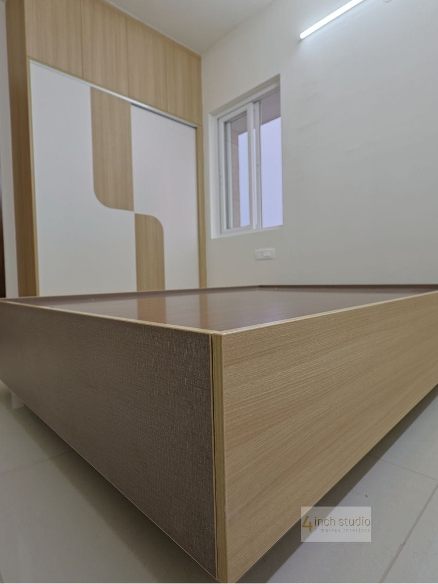 Bedroom with oak-laminate platform bed base facing a matching two-tone wardrobe by the window, Hyderabad