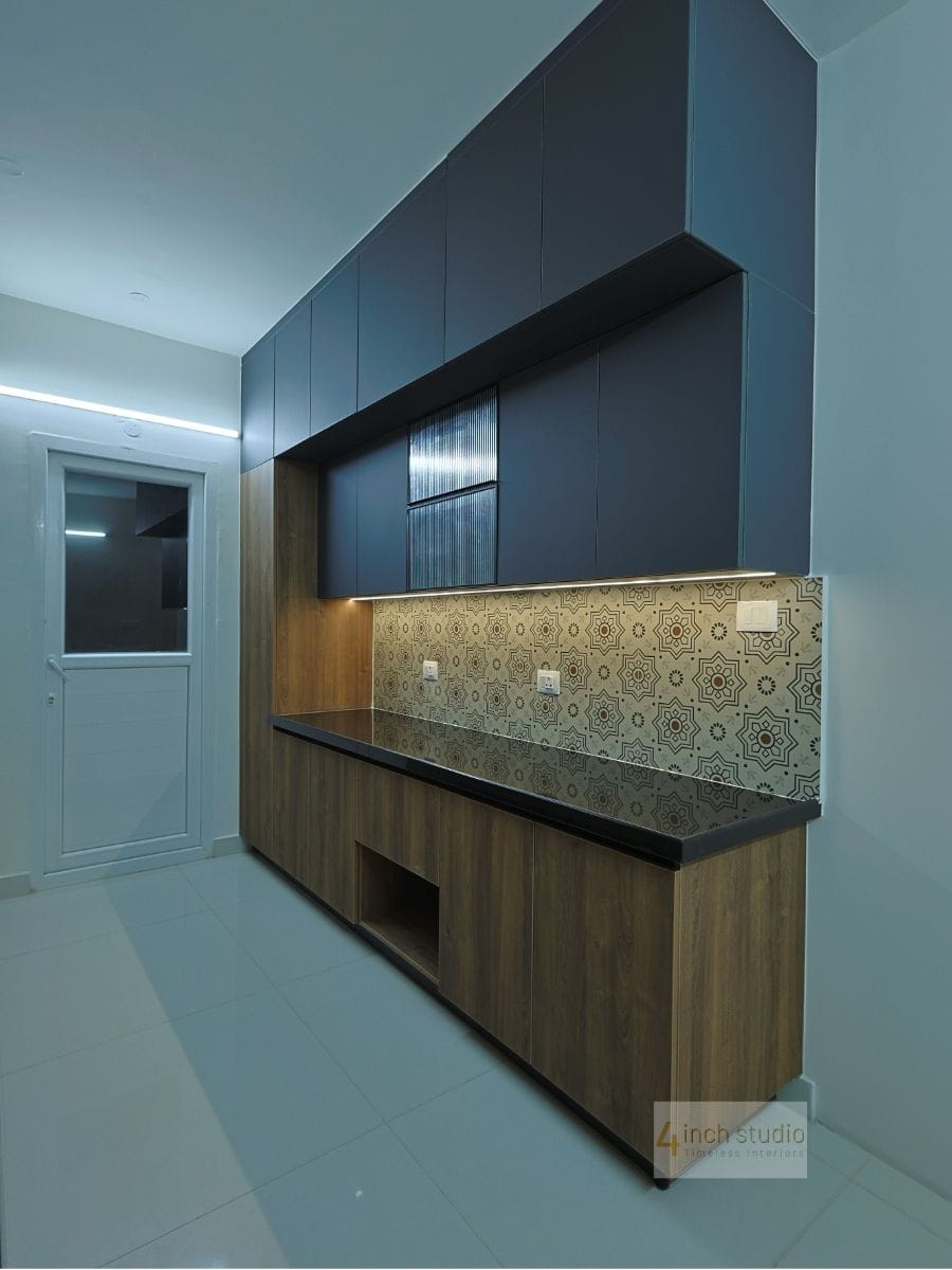 Kitchen crockery unit with navy wall cabinets, woodgrain base, black granite counter and ornate tile backsplash, Hyderabad
