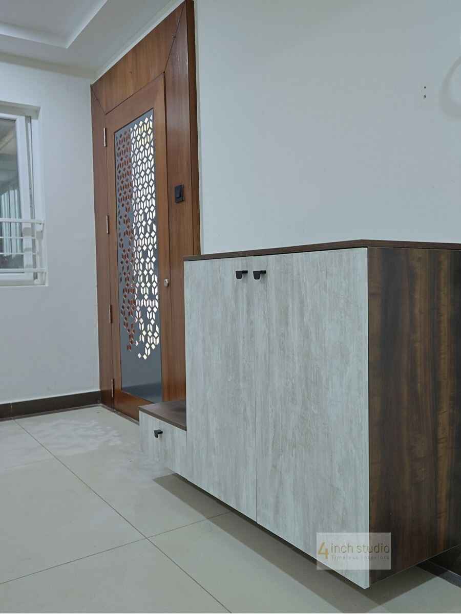 Foyer with light travertine-finish shoe cabinet and teak jali entry door over tiled flooring, Hyderabad