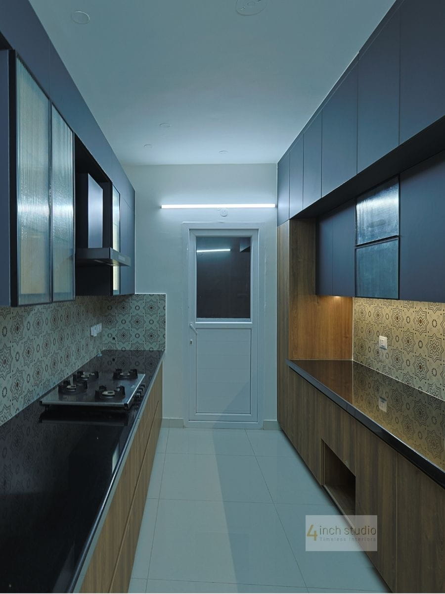 Parallel kitchen in navy and walnut laminate with black countertop, gas hob and patterned tile dado, Hyderabad
