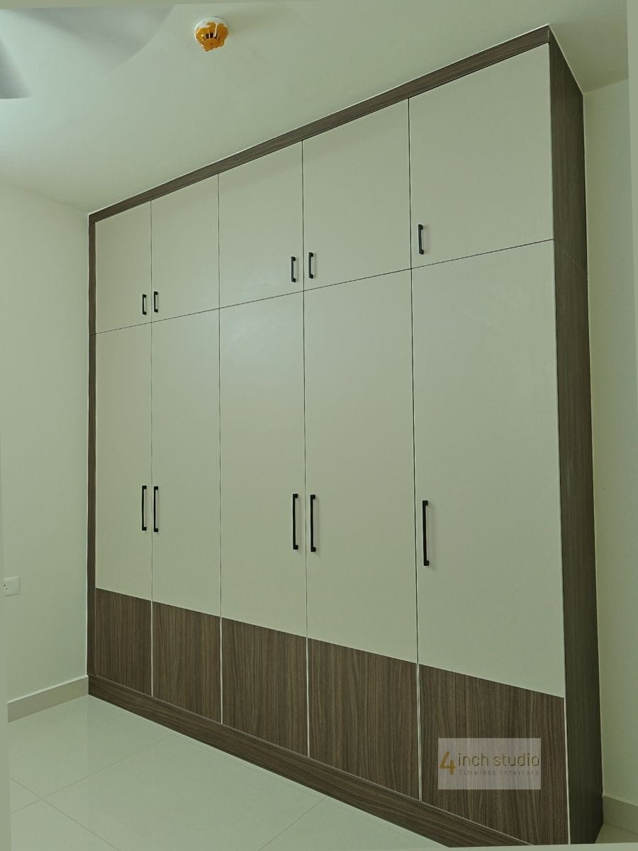 Five-door bedroom wardrobe in cream laminate with woodgrain trim and base band, Hyderabad apartment