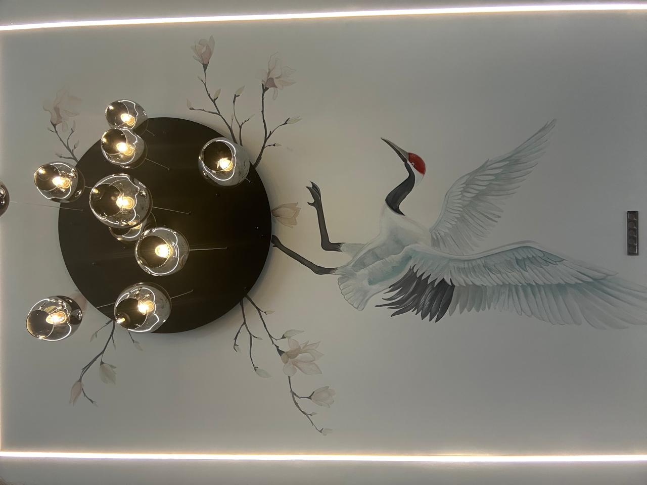 Hand-painted crane and magnolia ceiling mural framed by a black disc chandelier of chrome globe pendants and LED cove light